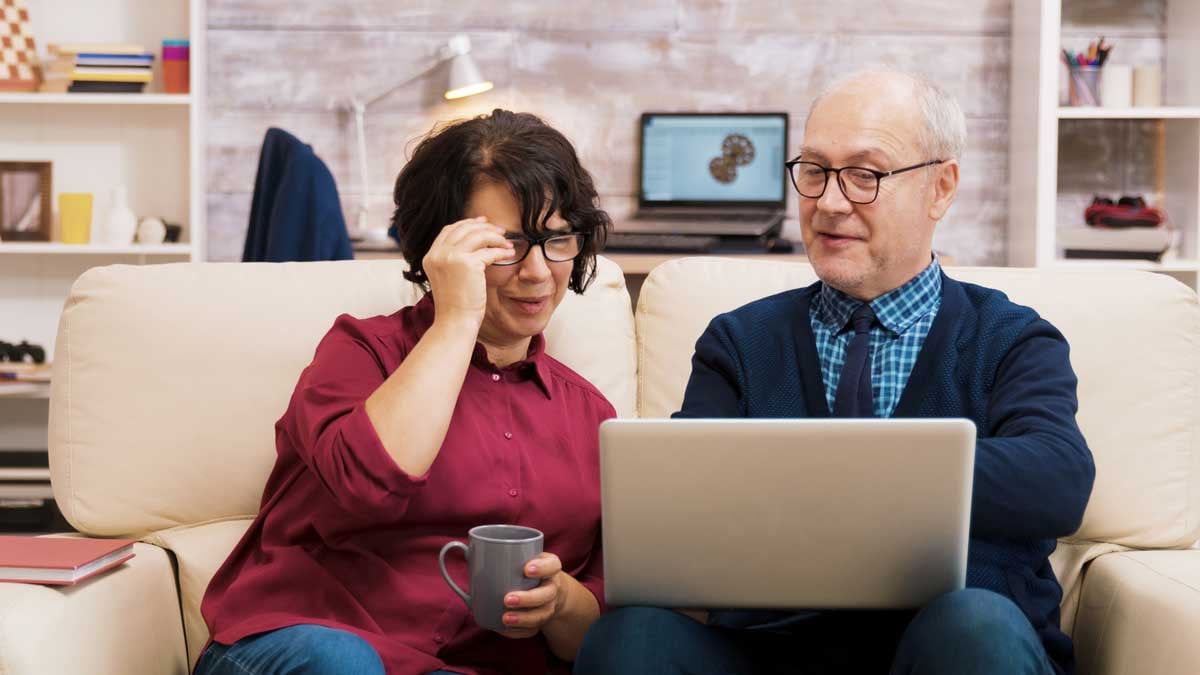 A couple taking part in a video meeting on their sofa at home